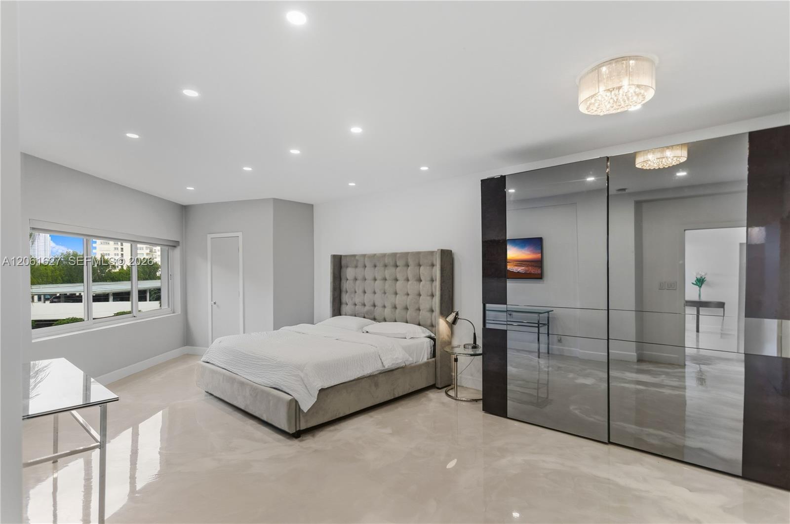 Room featuring polished stone flooring, recessed ceiling lighting, a flush-mount crystal-style light fixture, and floor-to-ceiling mirrored closet doo