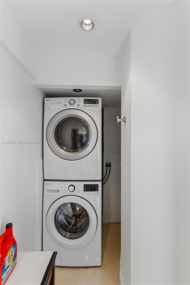 Stackable white front-load washer and dryer unit with recessed ceiling lighting