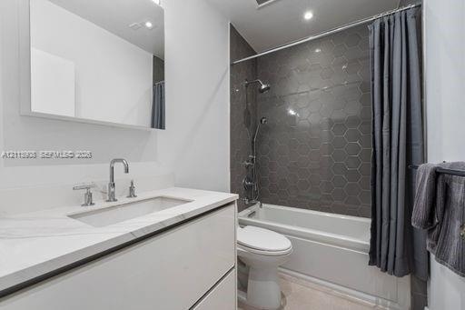 Bathroom featuring a floating vanity with a stone-top integrated sink, chrome widespread faucet, frameless wall-mounted mirror, and a shower-tub combi