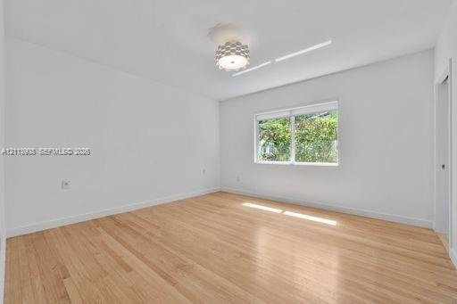 Room featuring wood-finish flooring, a contemporary geometric flush-mount light fixture, and a single-pane window