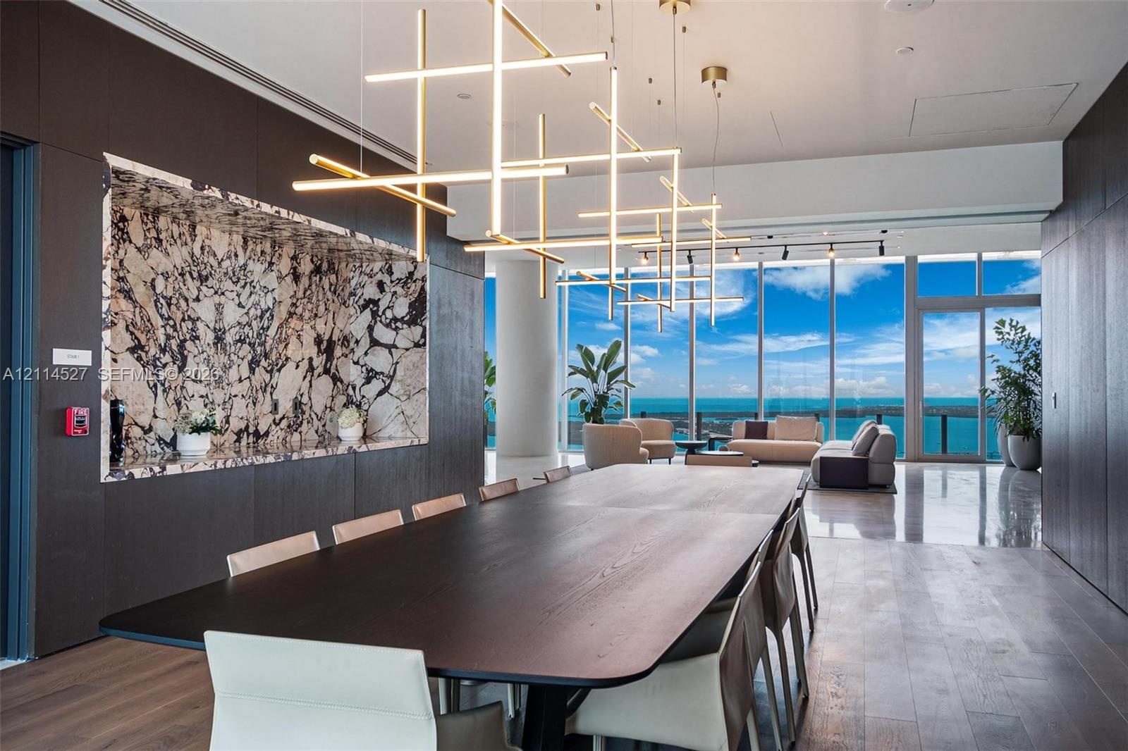 Floor-to-ceiling glass windows, custom built-in cabinetry featuring patterned stone inlay, linear geometric pendant lighting, wood-finish flooring, an