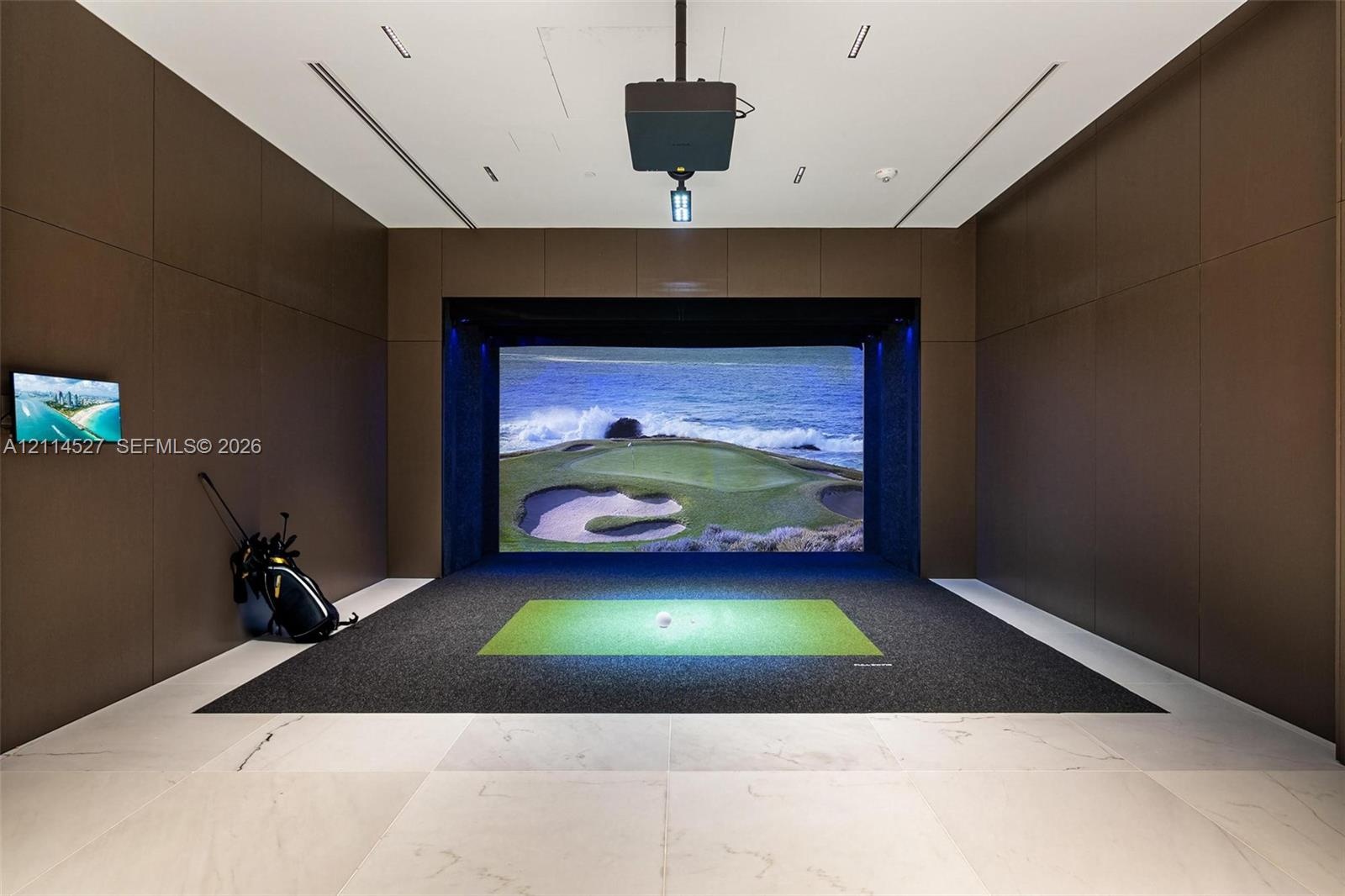 Recreation room featuring floor-to-ceiling wood-paneled walls, large-format tile flooring, a recessed ceiling projector, and a built-in digital sports