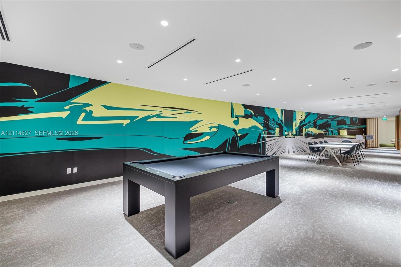 Expansive interior space featuring a large-scale graphic wall mural, recessed ceiling lighting, and integrated sound system speakers