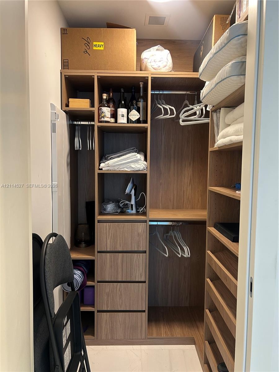 Custom closet organization system featuring wood-finish cabinetry, integrated shelving, four pull-out drawers, and dual hanging rods