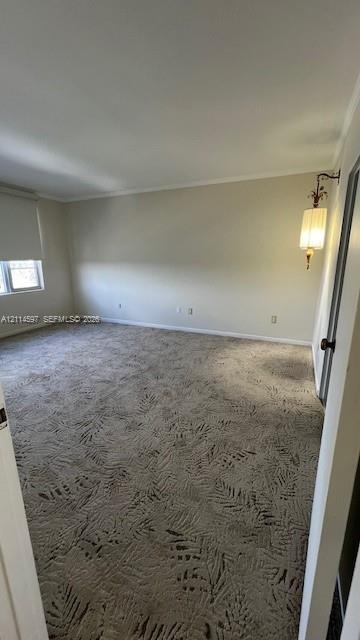 Spacious interior room featuring patterned wall-to-wall carpeting, neutral wall coloring, and an ornate wall-mounted light fixture