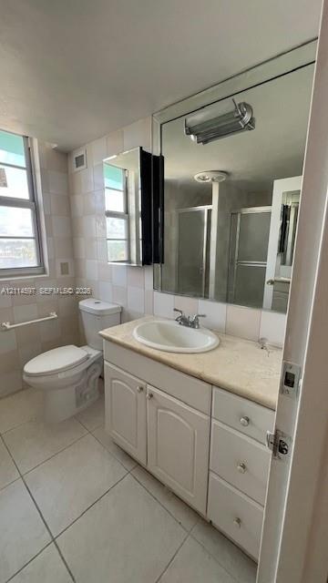 Bathroom featuring a white vanity cabinet with stone-finish countertop, oval undermount sink, expansive wall-to-wall mirror, and light-tone tile floor