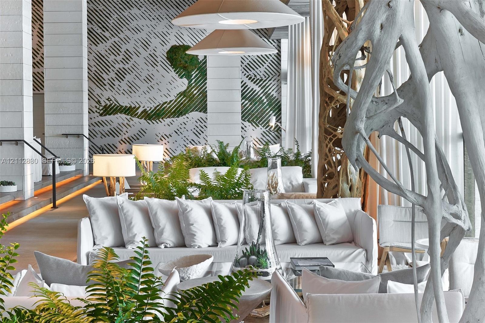 Expansive interior featuring large-format stone wall cladding, custom sculpted organic wood pillar, recessed floor accent lighting, and dual conical p