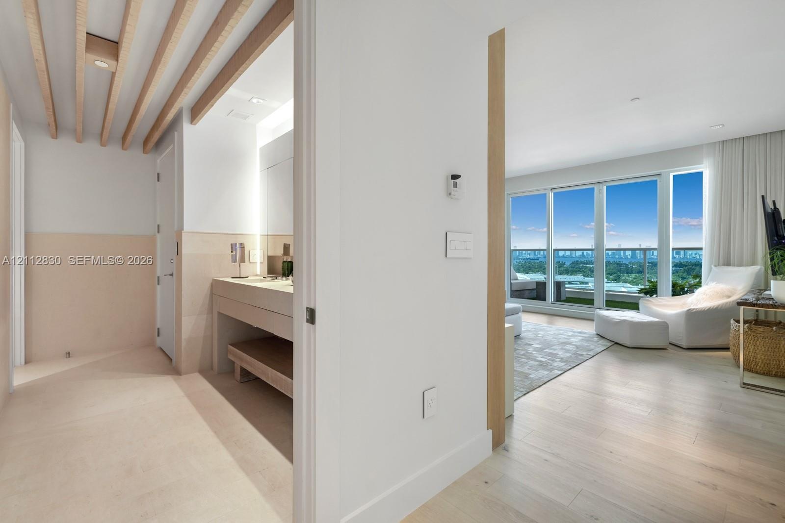 Light-filled interior featuring floor-to-ceiling windows, wood-finish flooring, exposed ceiling beams, a built-in vanity with under-counter shelving, 