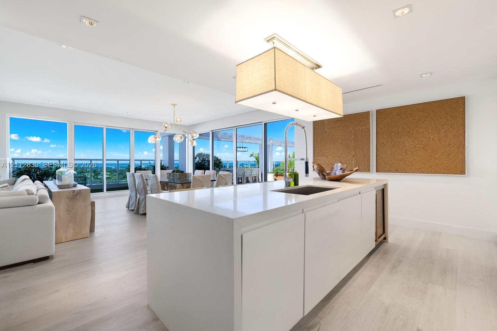 Kitchen island with stone-finish countertop, integrated sink, and built-in under-counter beverage chiller, complemented by wood-finish flooring, reces
