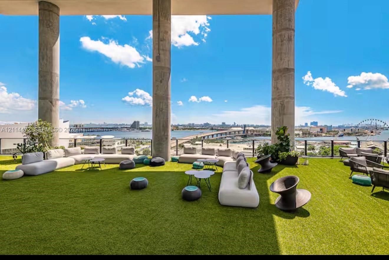 Expansive outdoor terrace featuring synthetic turf flooring, floor-to-ceiling structural concrete columns, and a perimeter metal railing