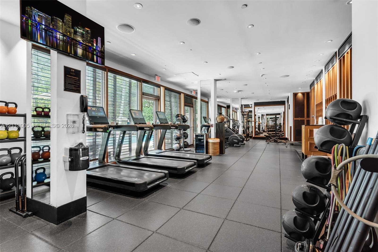 Fitness center featuring large-format floor tile, expansive floor-to-ceiling windows, recessed lighting, and wall-mounted mirrors