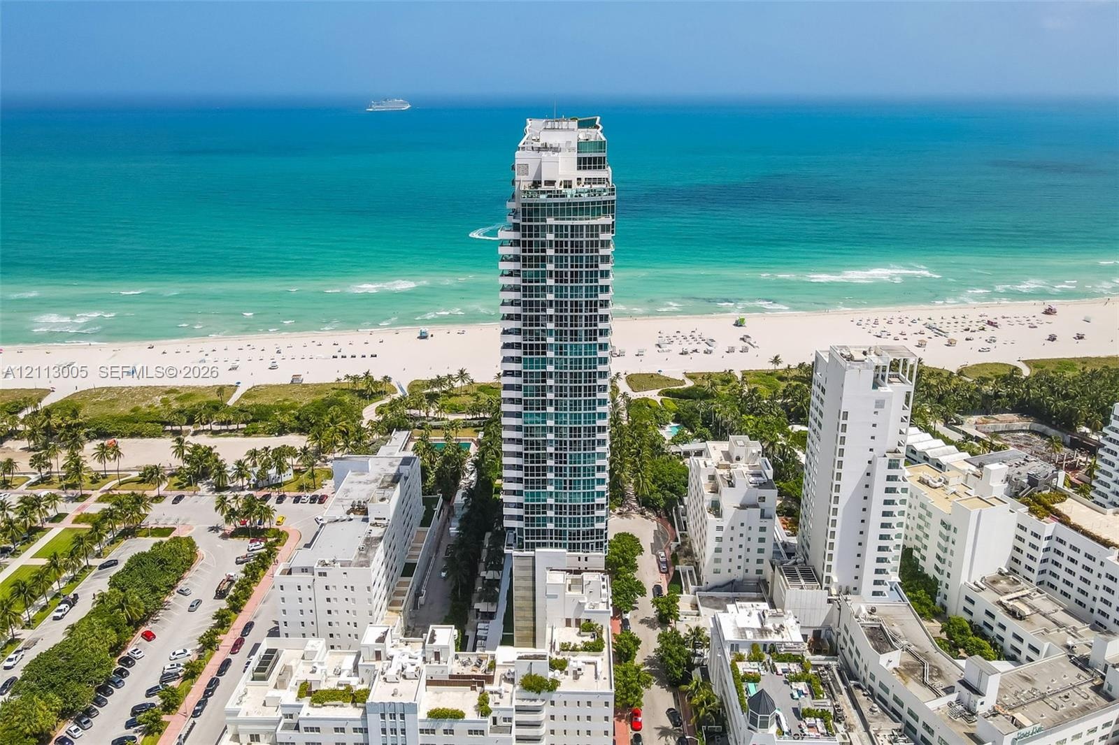 High-rise residential tower featuring a glass facade, multiple balconies, and an oceanfront location