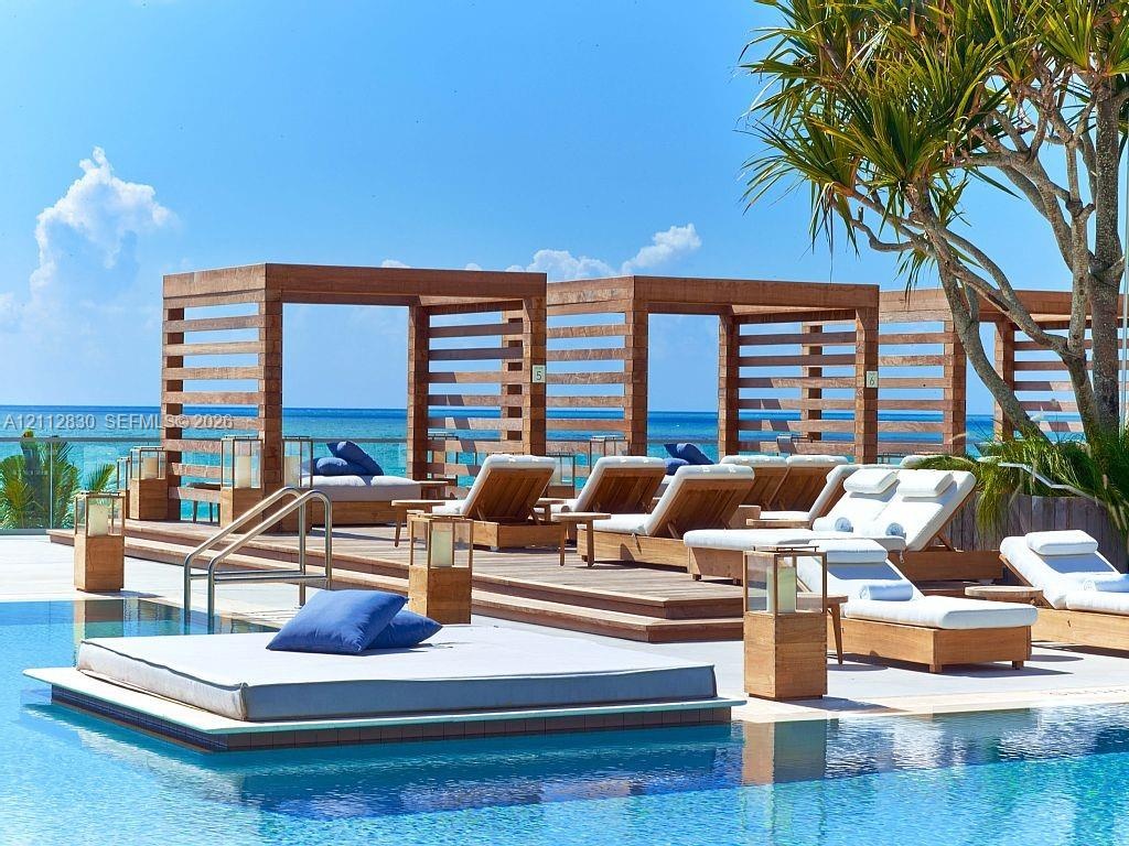 Swimming pool area featuring a stepped wooden deck, custom built-in wood-frame cabanas, and integrated lantern lighting