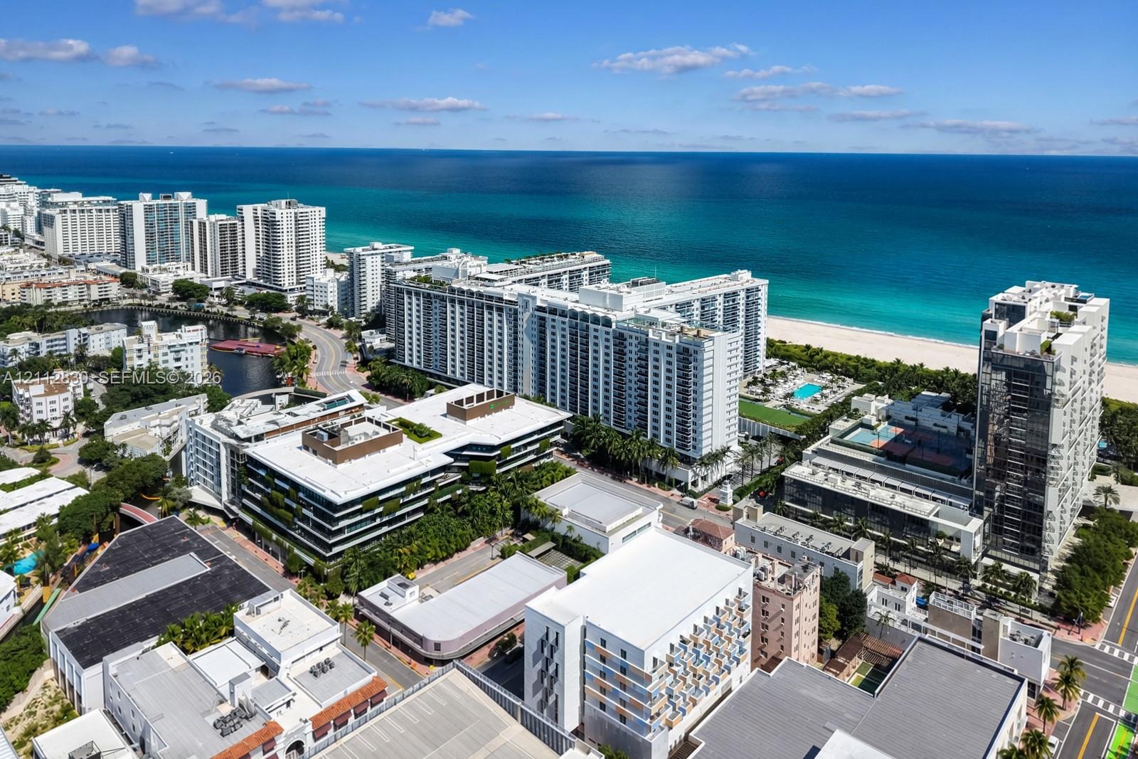Aerial perspective of a coastal residential district featuring direct oceanfront proximity, sandy beach access, high-rise architecture, and expansive 