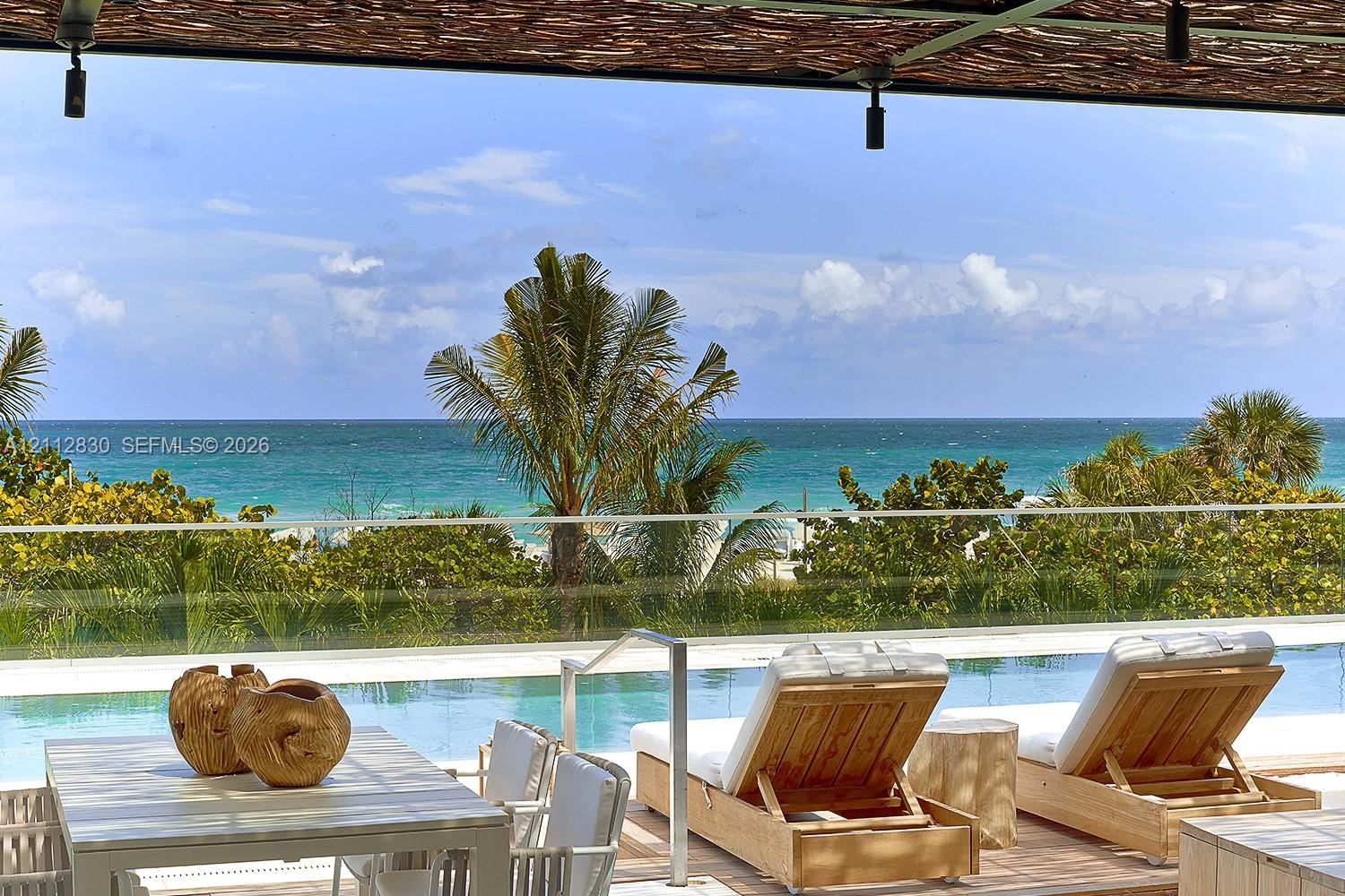 Outdoor terrace featuring a swimming pool with a glass railing and direct ocean exposure