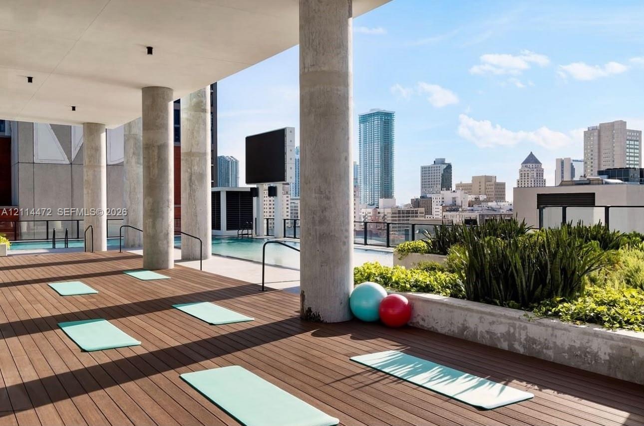 Rooftop terrace featuring wood-finish decking, concrete columns, a swimming pool, and built-in concrete planters