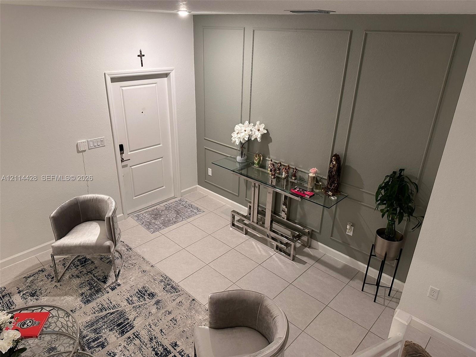 Entryway featuring neutral tile flooring, a six-panel door, and an accent wall with decorative picture frame molding