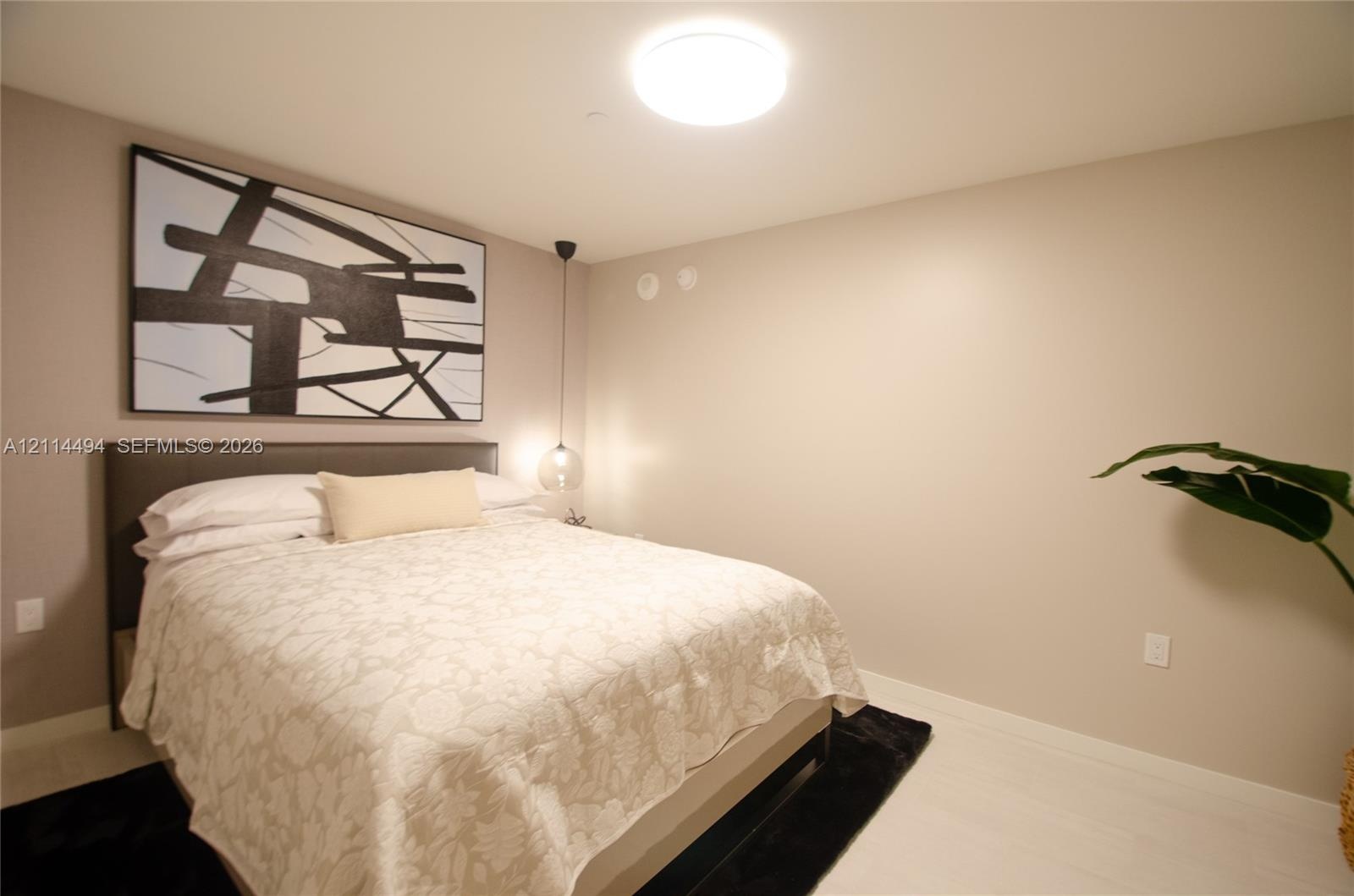 Neutral interior featuring light-toned wood-finish flooring, a contemporary flush-mount ceiling light, and a single pendant light fixture