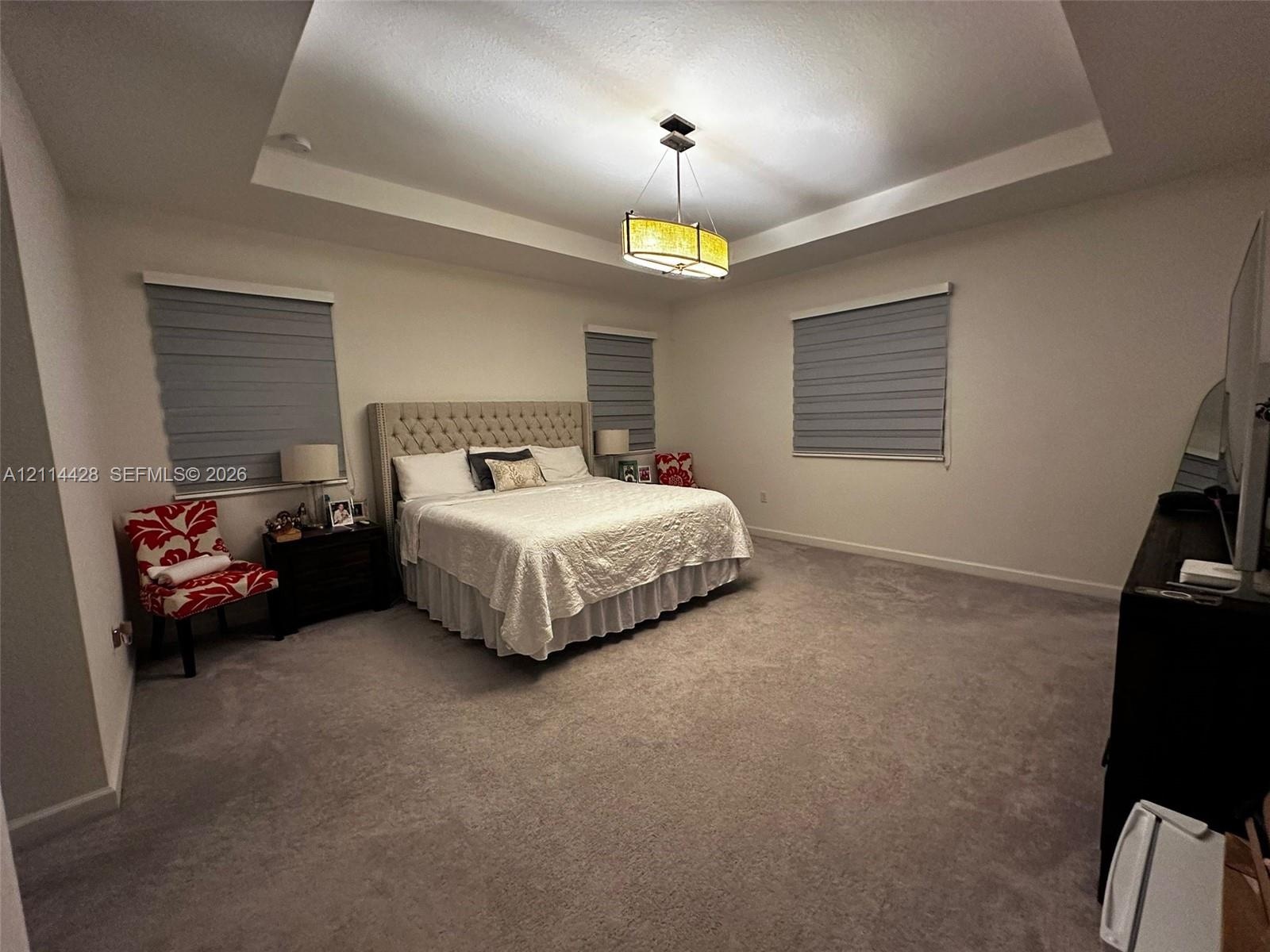 Tray ceiling with a central pendant light fixture and three windows with dual-layer cellular shades
