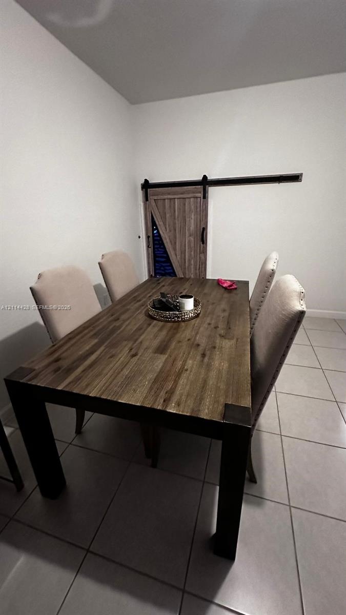 Neutral ceramic tile flooring and sliding wood-finish barn door with black iron hardware