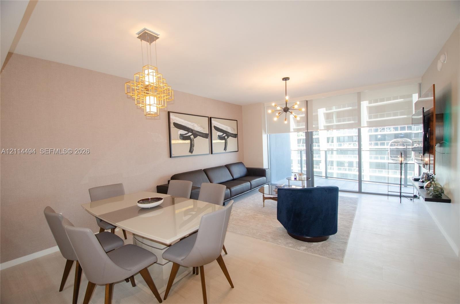 Open-concept living space featuring wood-finish flooring, floor-to-ceiling windows, modern geometric pendant lighting, an industrial-style chandelier,