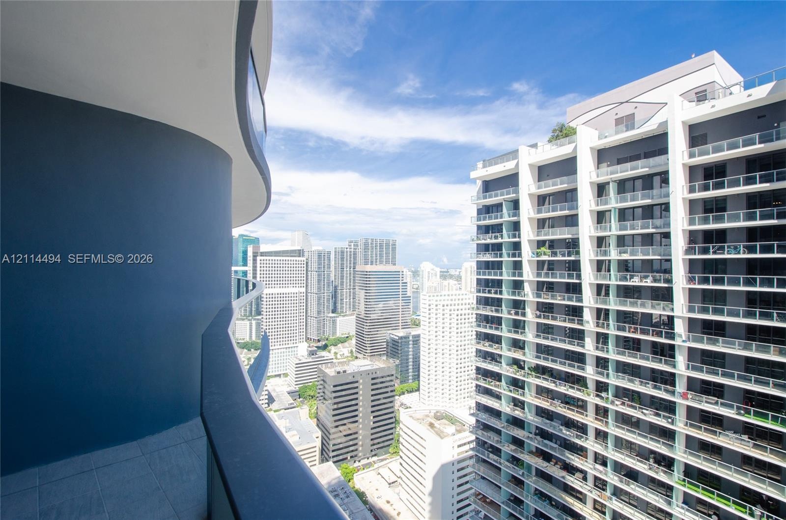 Curved balcony featuring tiled flooring, glass panel railing, and cityscape scenery