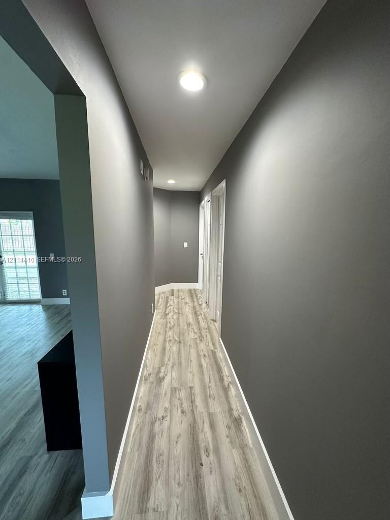 Hallway featuring wood-finish flooring, neutral-toned walls, and recessed ceiling lighting