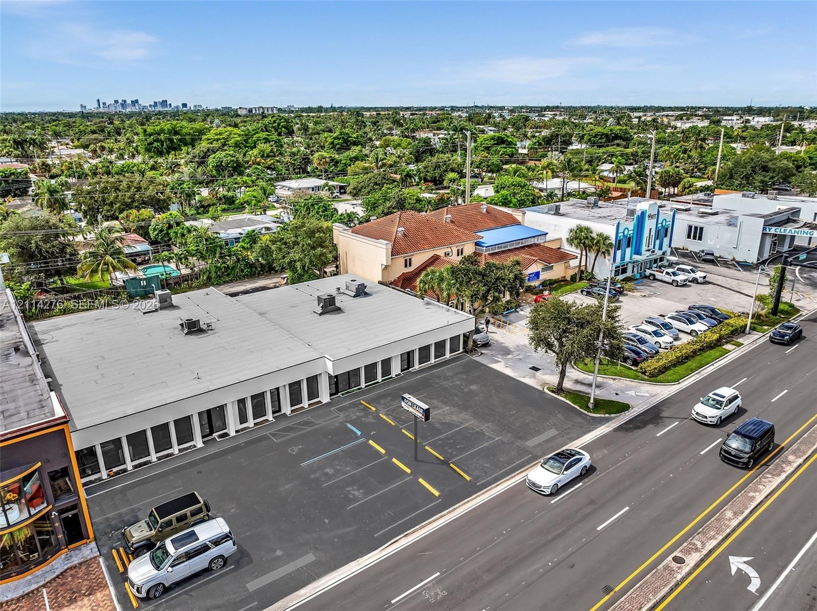 Commercial property featuring a flat-roof structure with glass-paneled storefronts and a dedicated asphalt parking lot with striped spaces