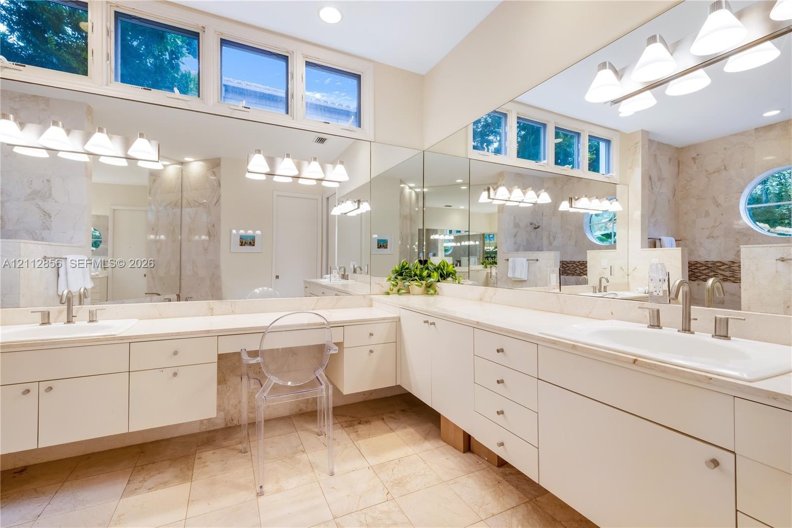 L-shaped vanity featuring a solid surface countertop, dual integrated sinks with brushed metal faucets, extensive built-in cabinetry, large-scale wall