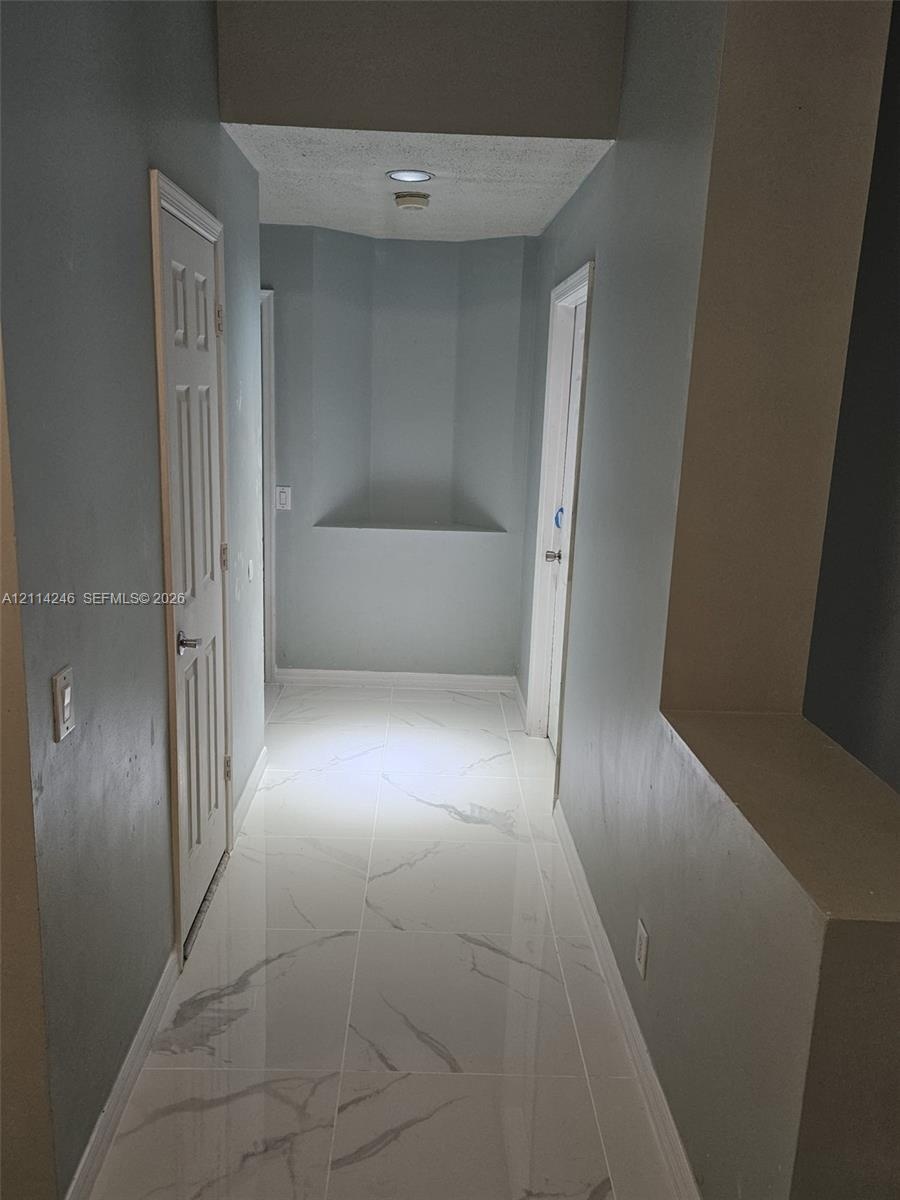 Hallway featuring large-format tile flooring with a veined finish, recessed wall niches, and paneled interior doors
