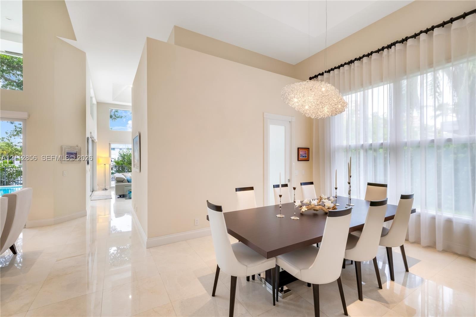 High ceilings, polished stone flooring, custom architectural pendant lighting, and oversized windows with drapery