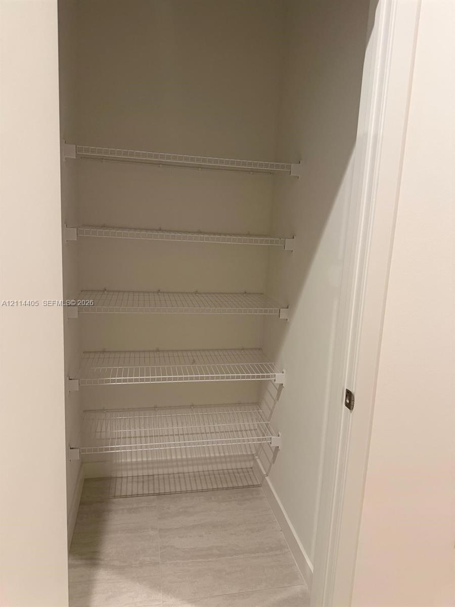 Storage space featuring five tiers of white wire shelving and tile flooring