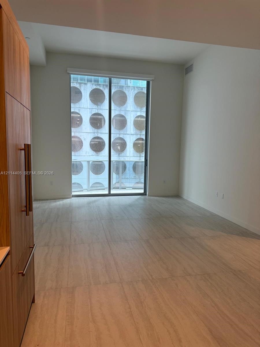 Floor-to-ceiling sliding glass doors, full-height wood-finish cabinetry, and large-format tile flooring