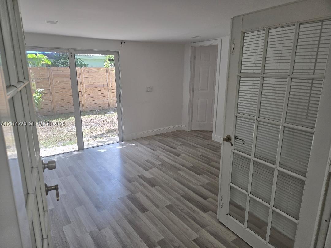 Interior space featuring wood-finish flooring, recessed lighting, and a multi-lite door with integrated blinds