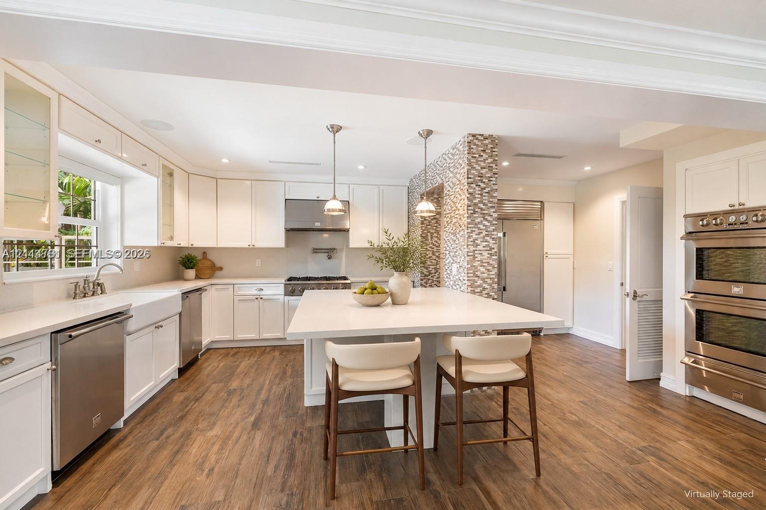 Kitchen featuring white cabinetry, an expansive central island with a solid surface countertop, wood-finish flooring, stainless steel built-in double 