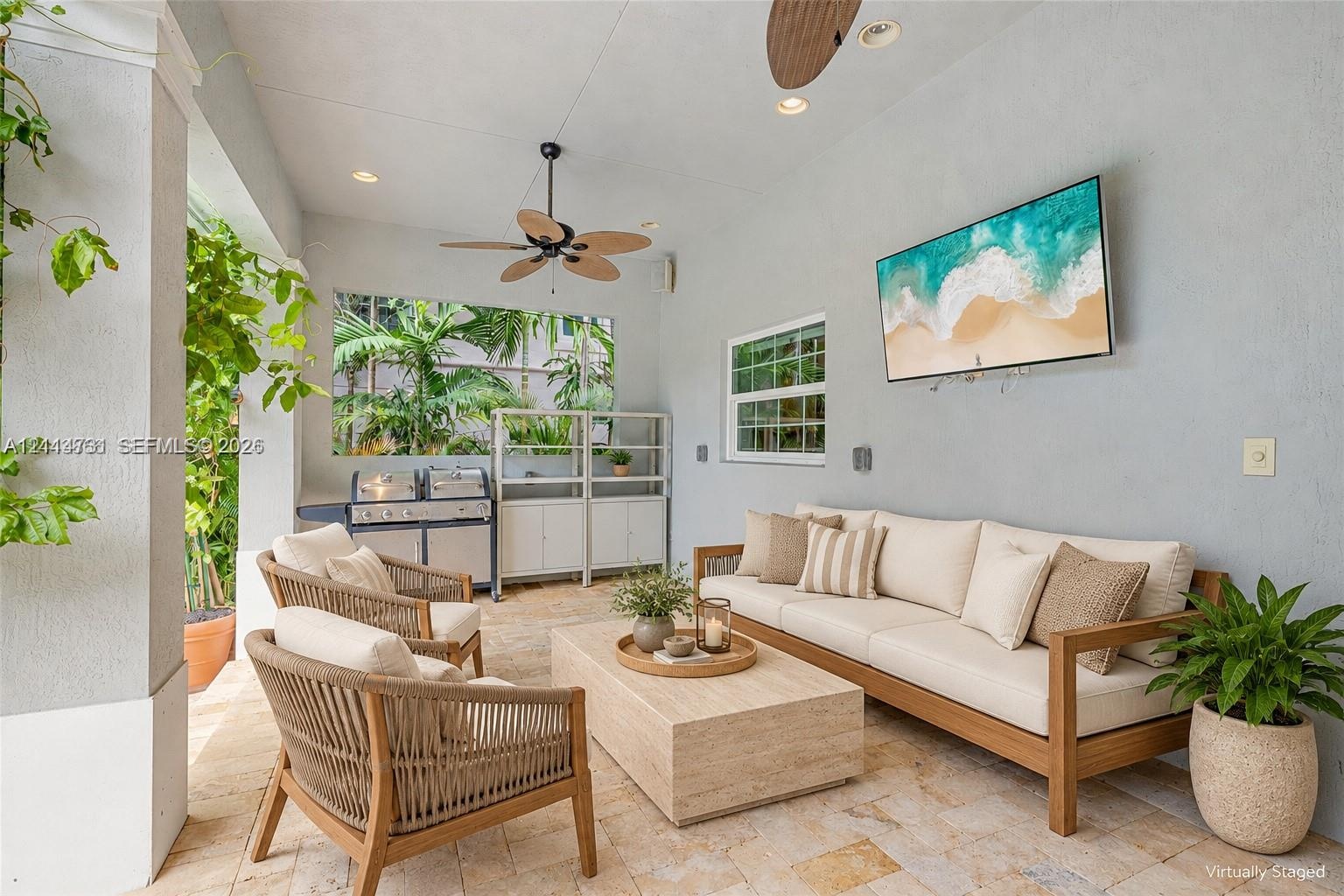 Covered patio featuring stone-tiled flooring, a built-in outdoor kitchen with stainless steel grill, recessed lighting, and a ceiling fan