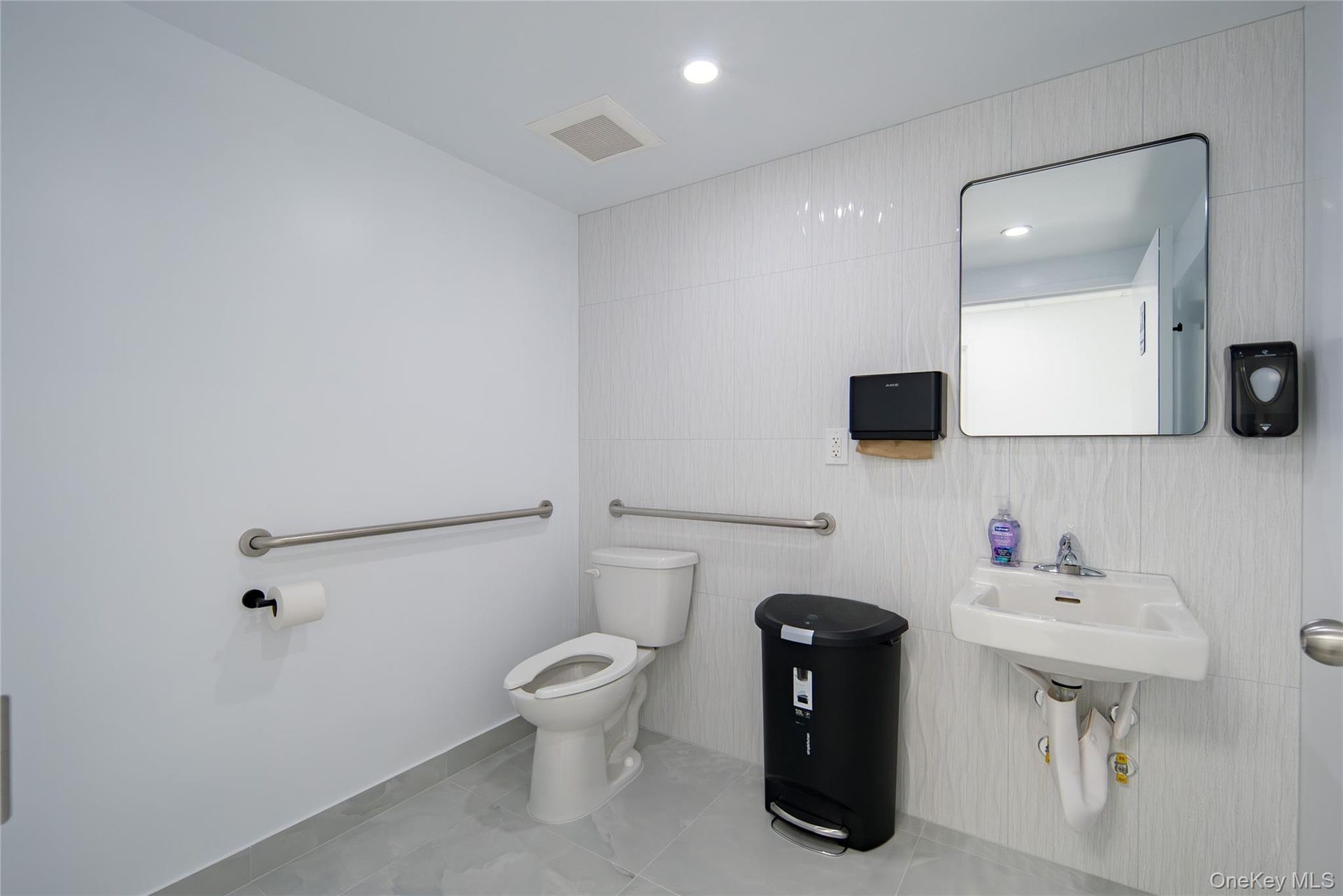 Half bath featuring light tile patterned floors, recessed lighting, and tile walls