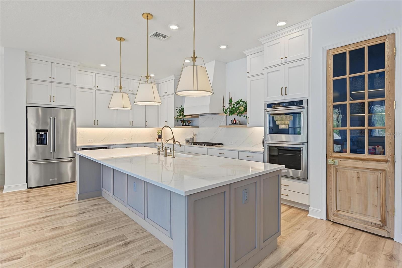 What a stunning kitchen with designer lighting and oversized island