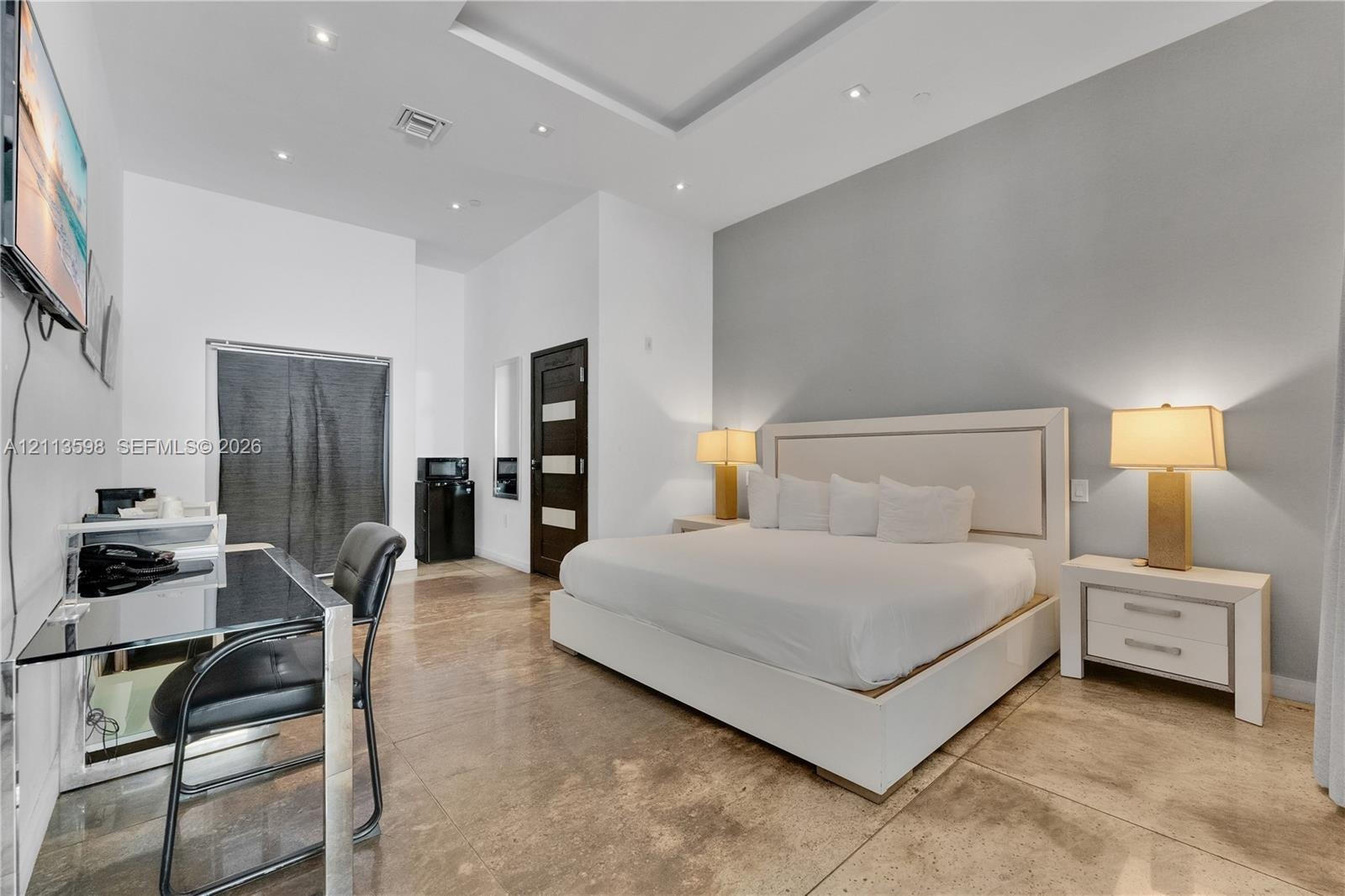Tray ceiling with recessed lighting, polished stone flooring, and a multi-toned wood door with glass inserts