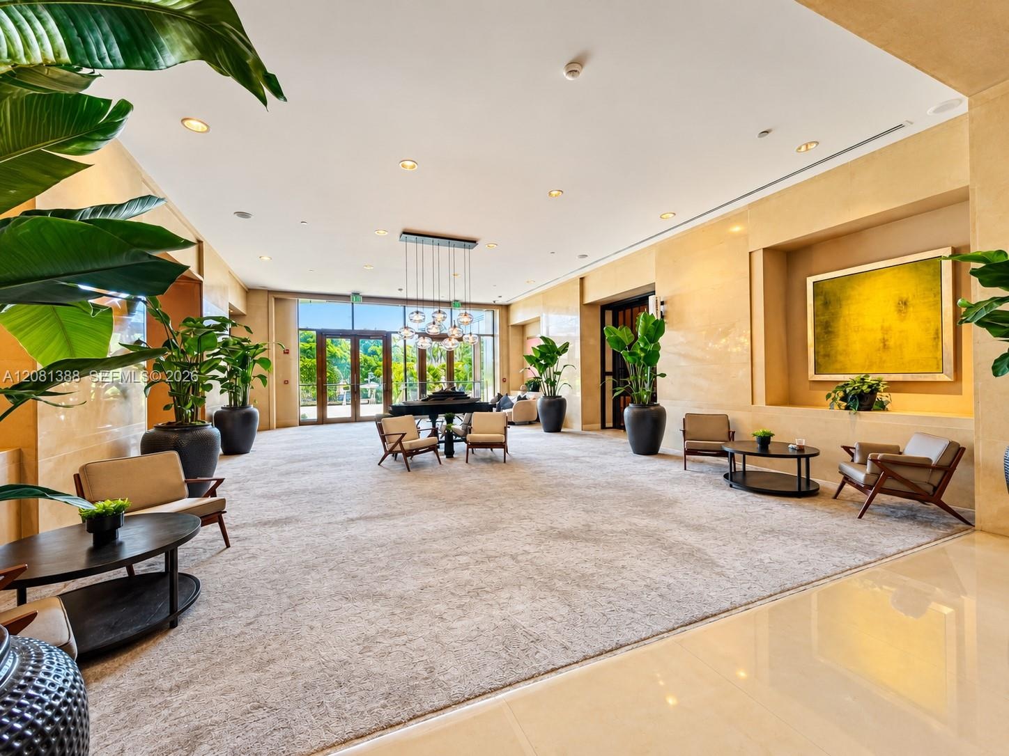 Expansive common area featuring stone-clad walls, recessed lighting, a modern multi-pendant chandelier, a built-in recessed display niche, and floor-t
