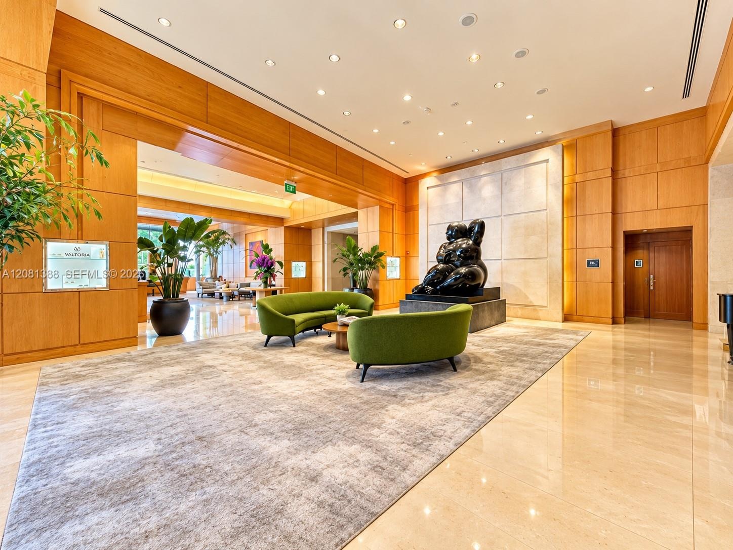 Expansive lobby featuring natural wood-paneled walls, polished stone flooring, recessed lighting, and a prominent stone-tiled accent wall