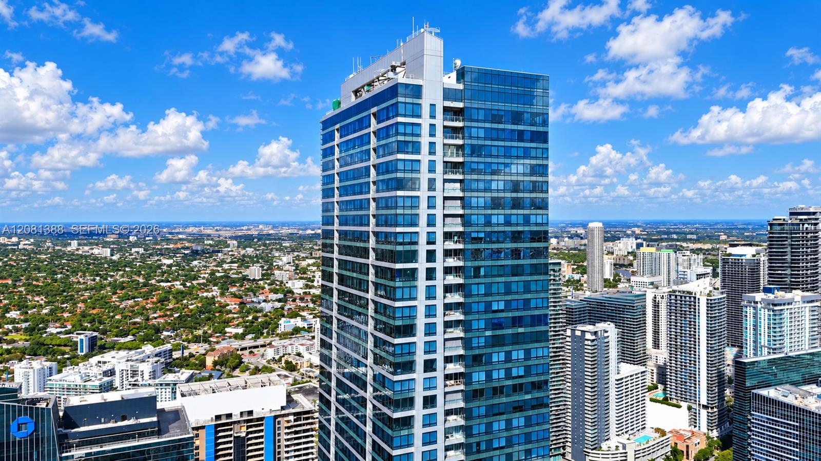 High-rise residential tower featuring a glass-curtain facade, recessed private balconies, and reinforced concrete structural elements