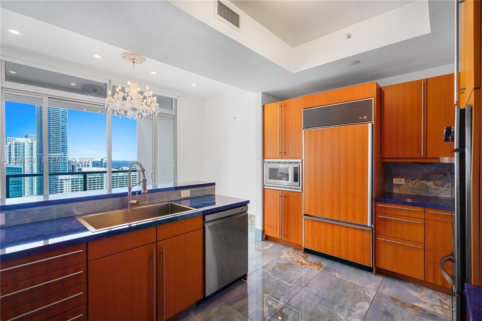 Kitchen featuring wood cabinetry, high-gloss stone countertops, stainless steel appliances, polished stone flooring, and expansive floor-to-ceiling wi