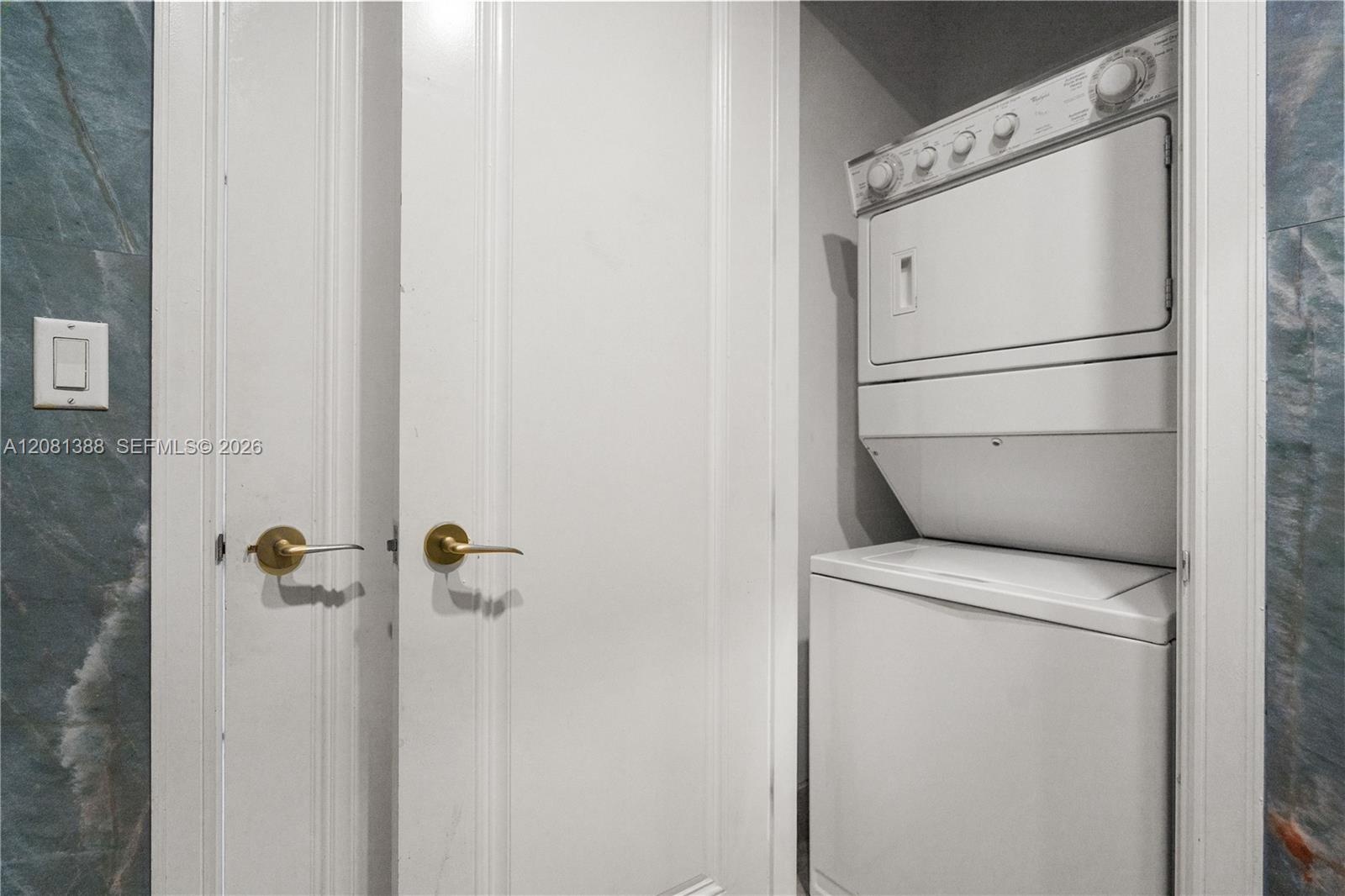 Stackable laundry unit featuring a white finish, enclosed by solid-core interior doors with metallic lever handles and framed by large-format, cool-to