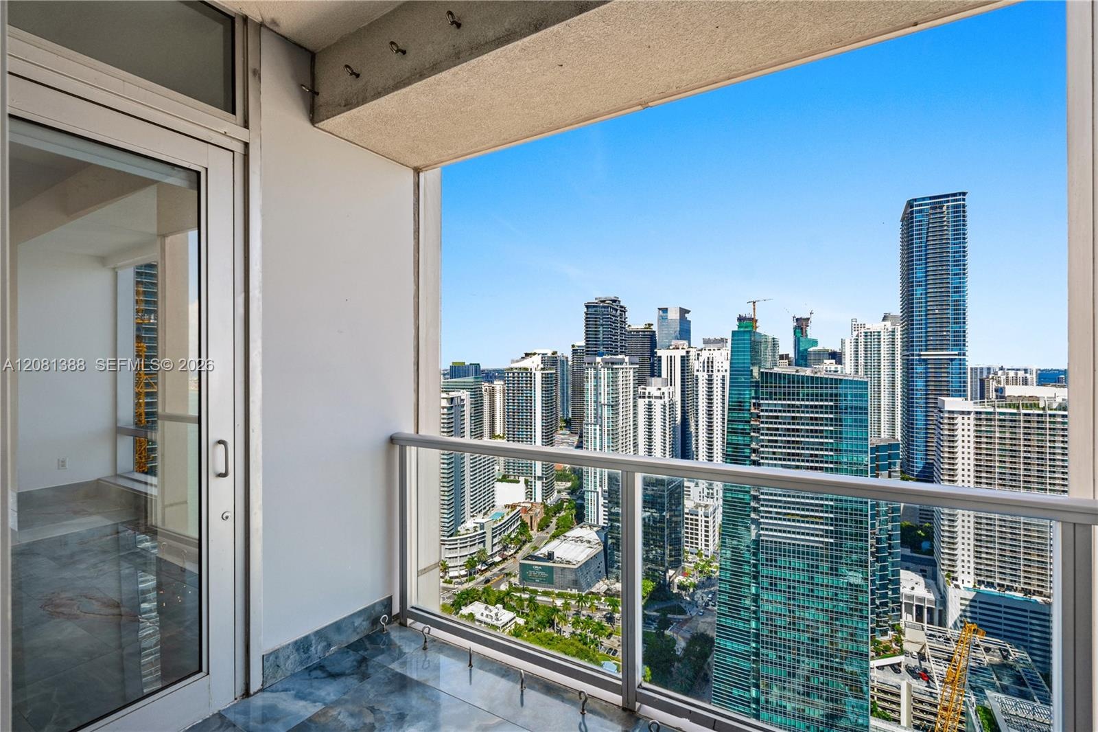Private balcony featuring stone tile flooring and a glass-paneled railing with a metal frame