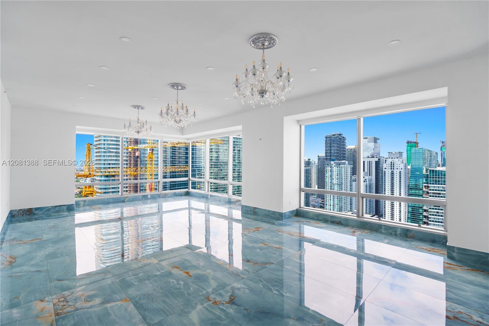Polished blue-toned stone flooring, triple crystal chandeliers, floor-to-ceiling windows, and recessed lighting