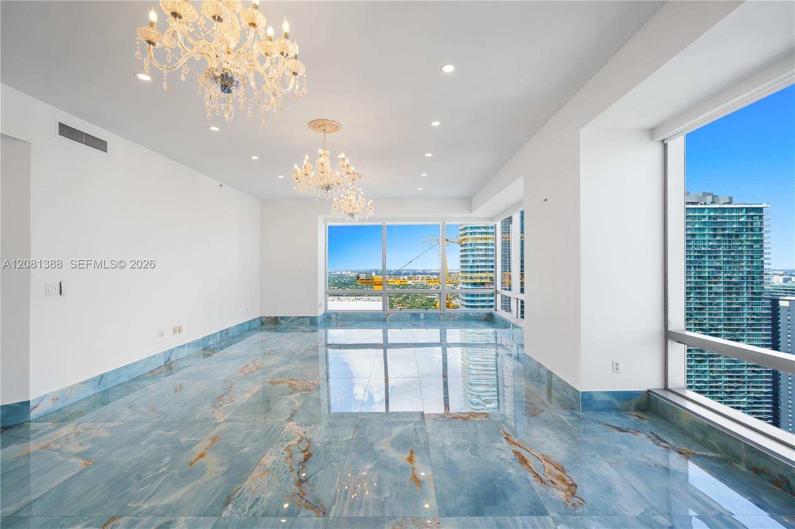 Polished stone flooring with prominent veining, floor-to-ceiling windows, recessed lighting, and multi-tiered crystal chandeliers