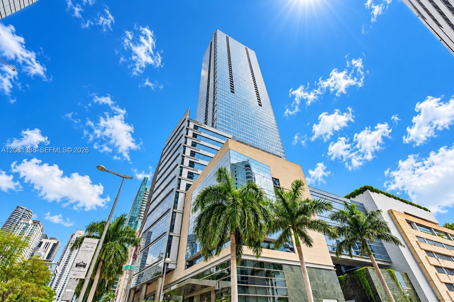 High-rise glass facade featuring modern architectural design, stone cladding, and mature palm tree landscaping