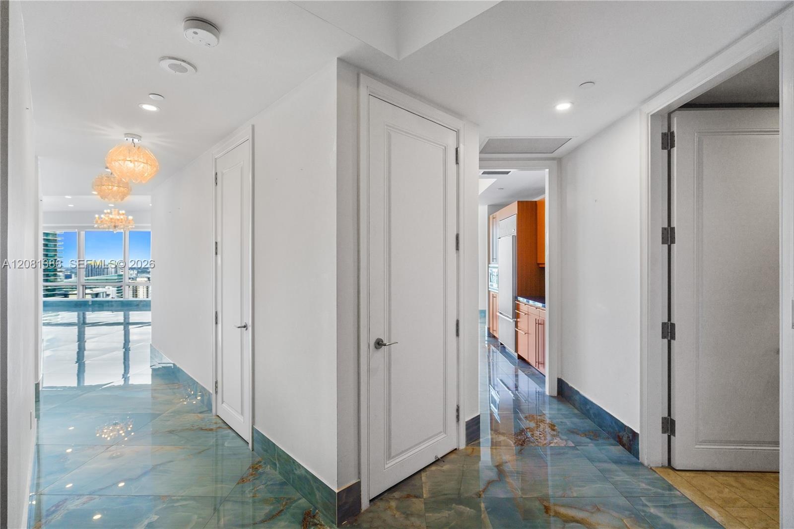 Polished stone flooring with blue and gold veining, multi-pendant dome light fixtures, solid-core interior doors, and floor-to-ceiling windows