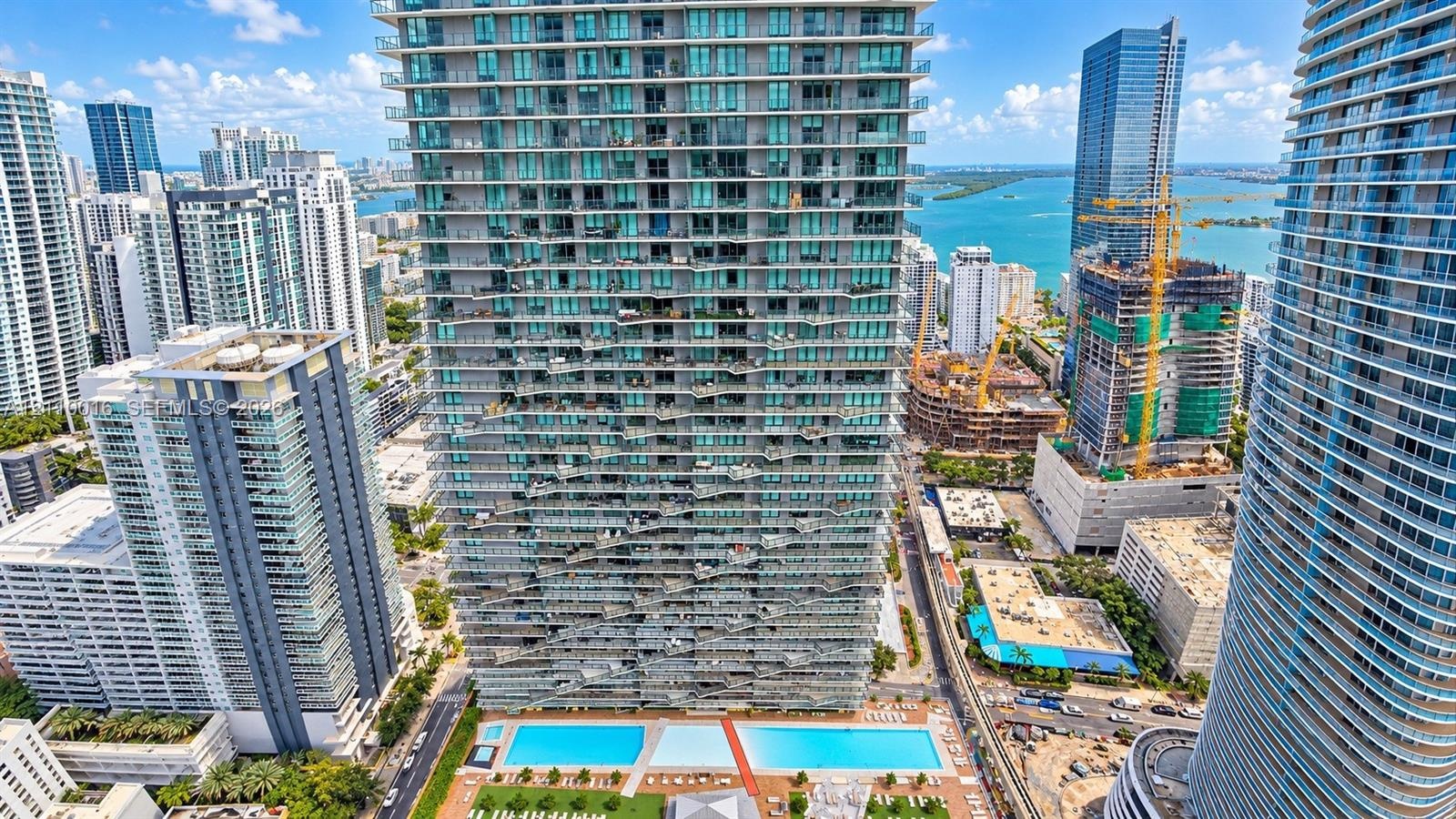 High-rise architecture featuring a curvilinear facade, tiered balconies with metallic railings, and dark-toned structural columns